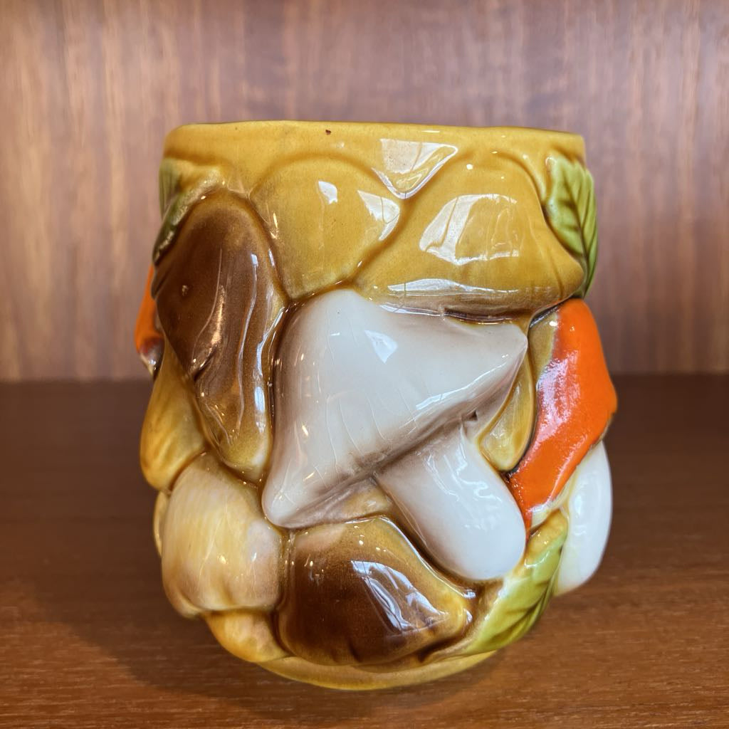 Decorative ceramic mug with mushroom design on a wooden surface
