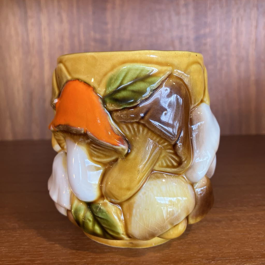 Decorative ceramic piece with leaf and mushroom design on a wooden surface