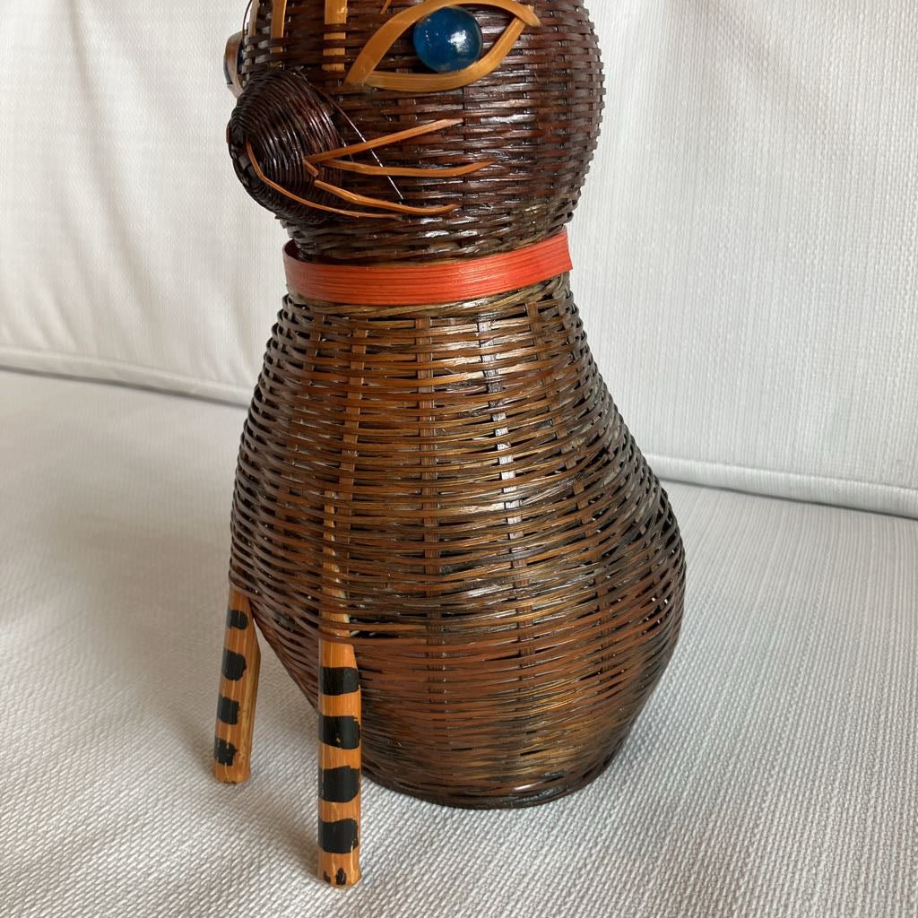 Wicker cat-shaped decorative item on a light gray surface with a white background