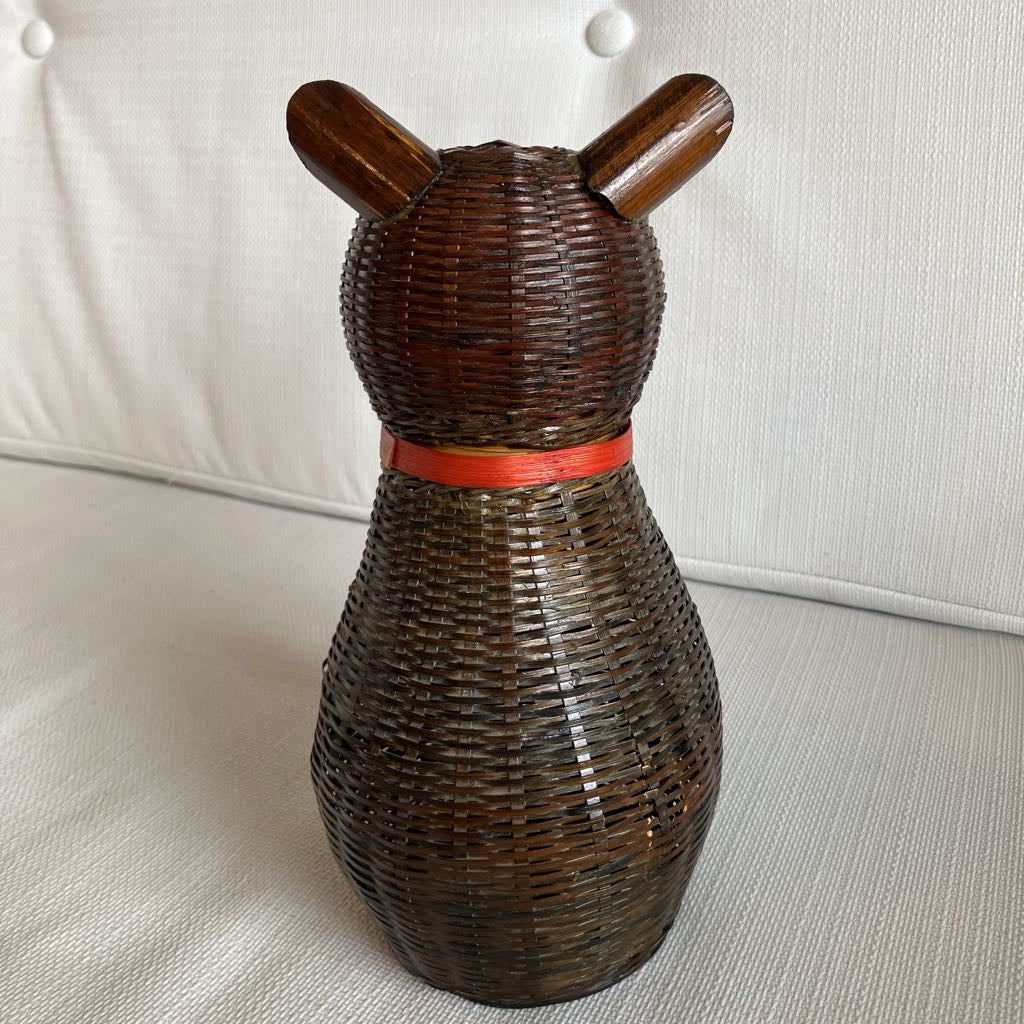 Wicker cat-shaped decorative item with wooden ears on a white surface