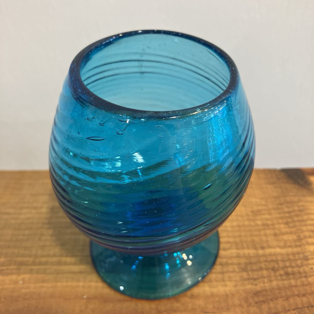 Blue glass vase with ribbed texture on a wooden surface