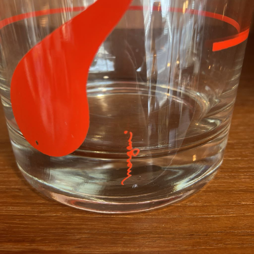 Clear glass with red logo on a wooden surface