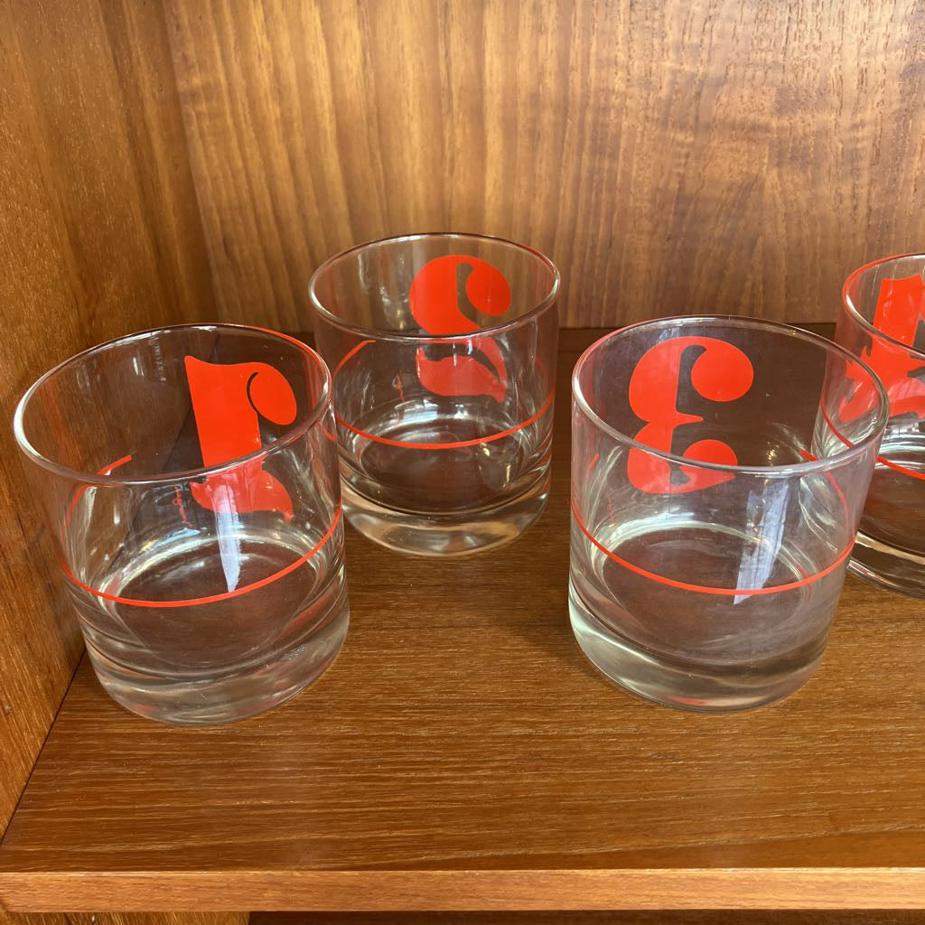 Clear glasses with red logo on a wooden shelf
