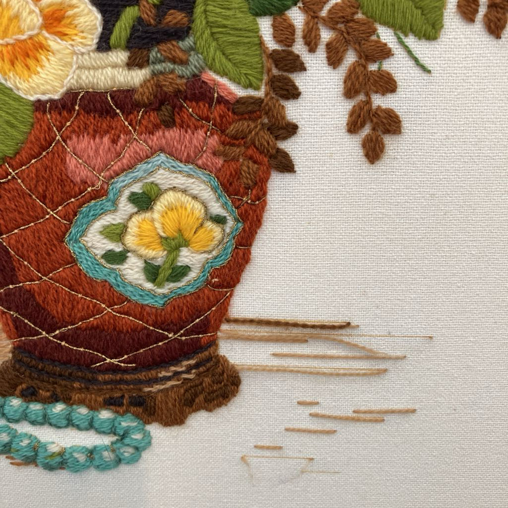Close-up of an embroidered vase with floral design on fabric