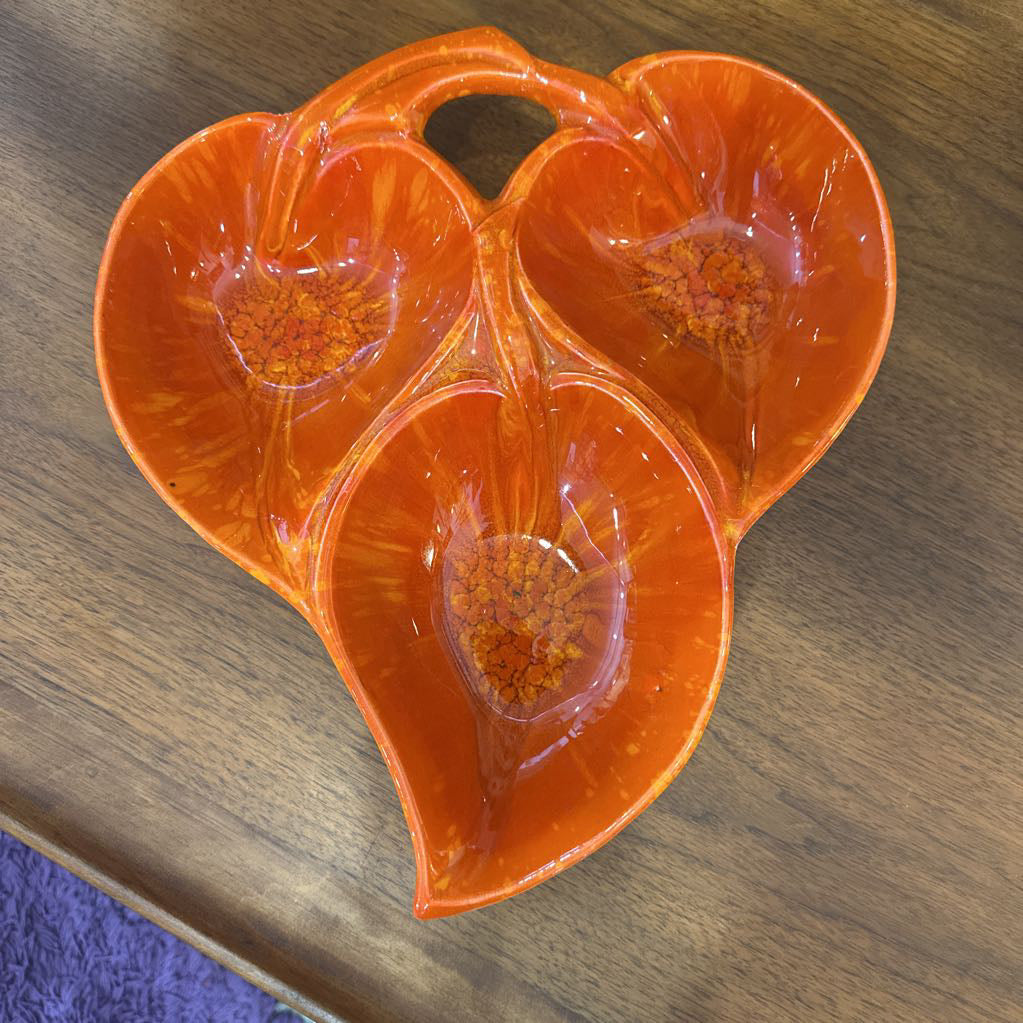 Orange ceramic leaf-shaped dish on a wooden surface