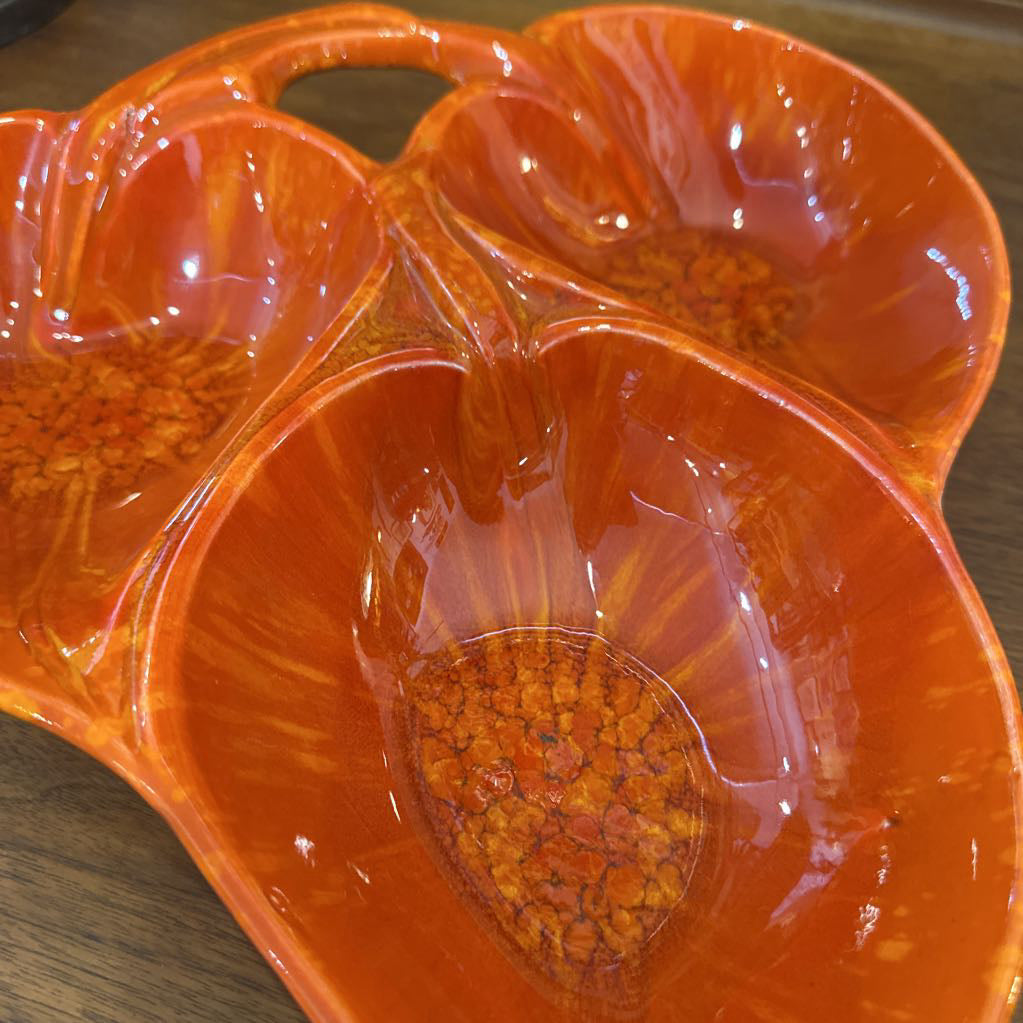 Orange ceramic leaf-shaped platter on a wooden surface
