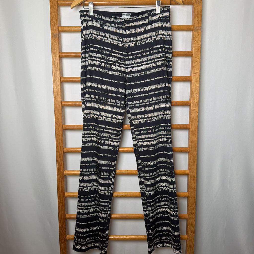 Black and white patterned pants hanging on a wooden rack against a plain background