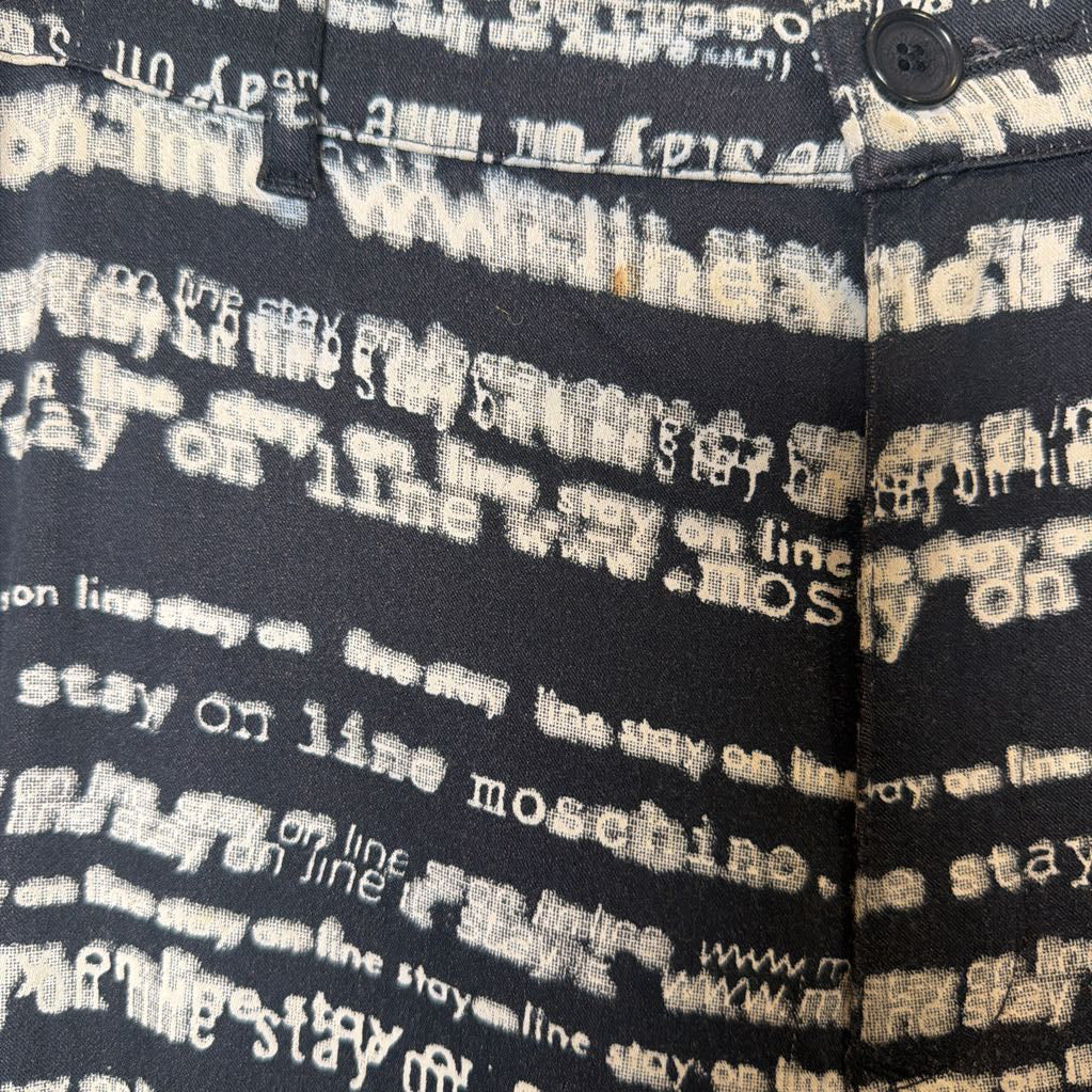 Textured fabric with 'Stay on line moschino' print on a black background