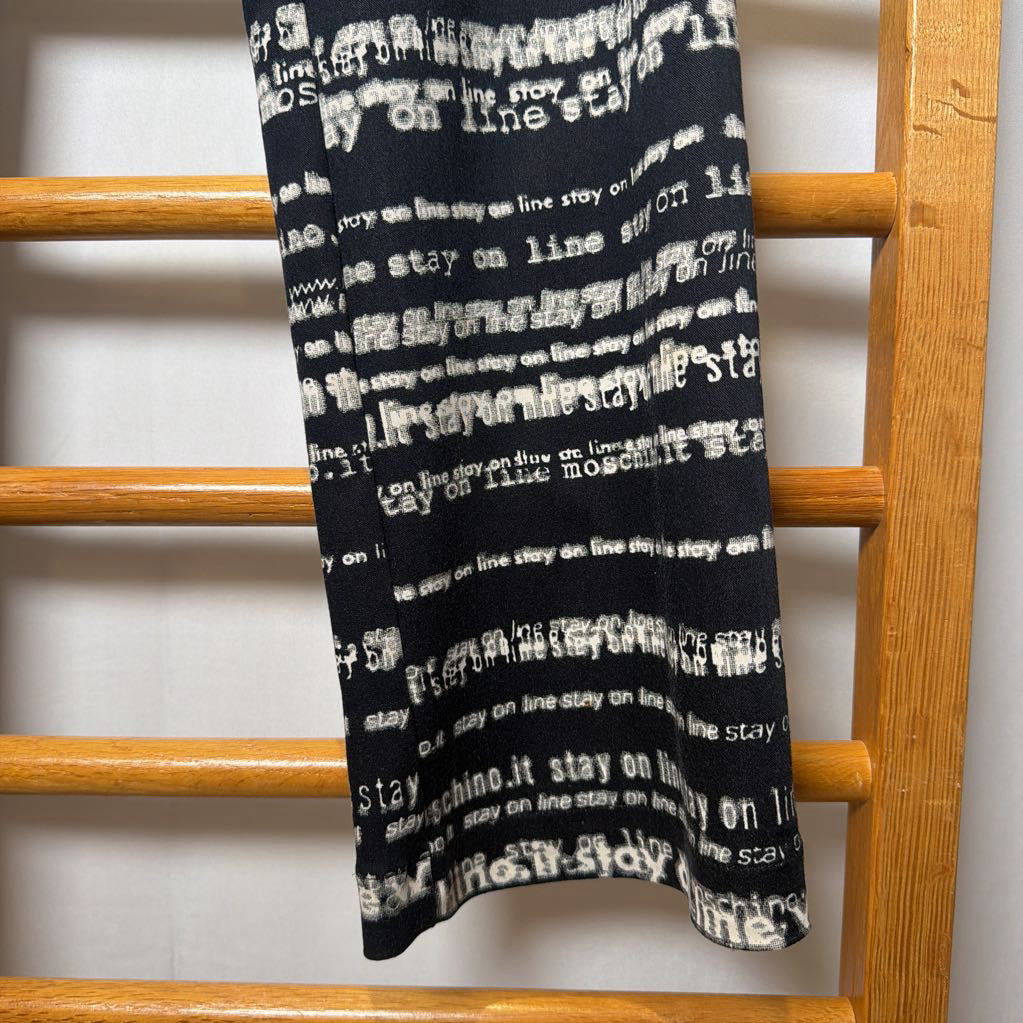 Black blanket with white text draped over a wooden rack.