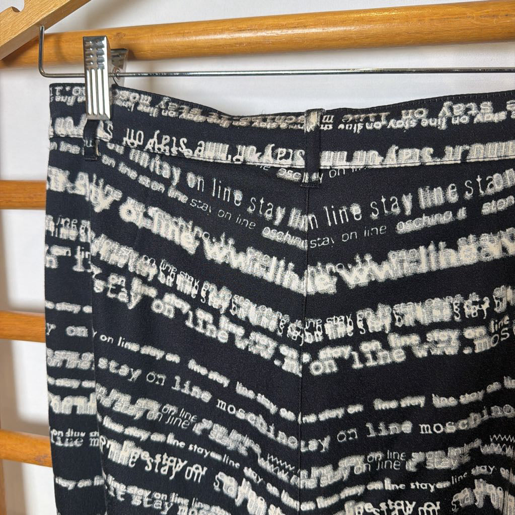 Black pants with white text pattern hanging on a rack