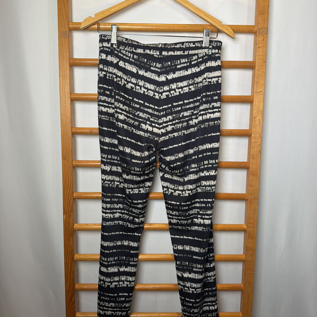Black and white patterned leggings hanging on a wooden rack against a white background