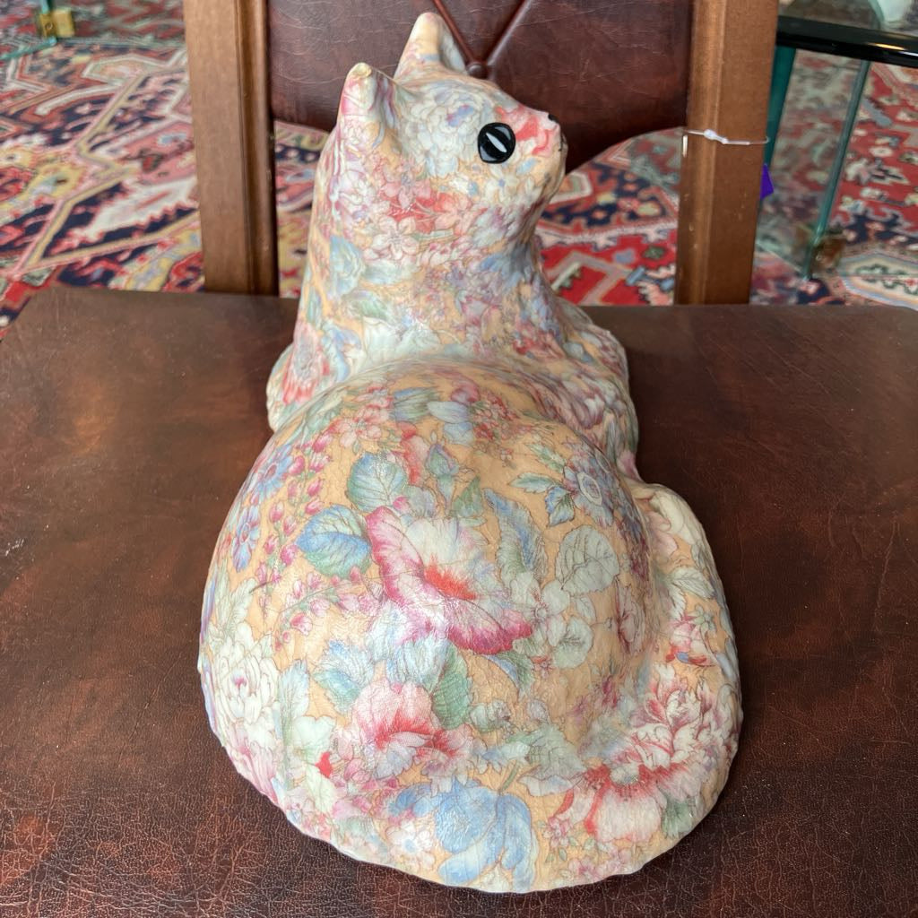 Decorative ceramic cat figurine with floral patterns on a wooden surface.