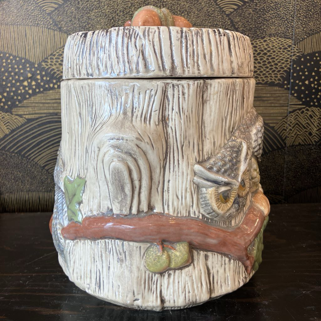 Decorative ceramic jar with nature-themed design on a dark surface