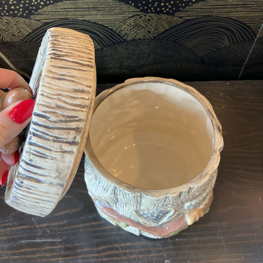 Ceramic container with a lid held by a hand on a wooden surface