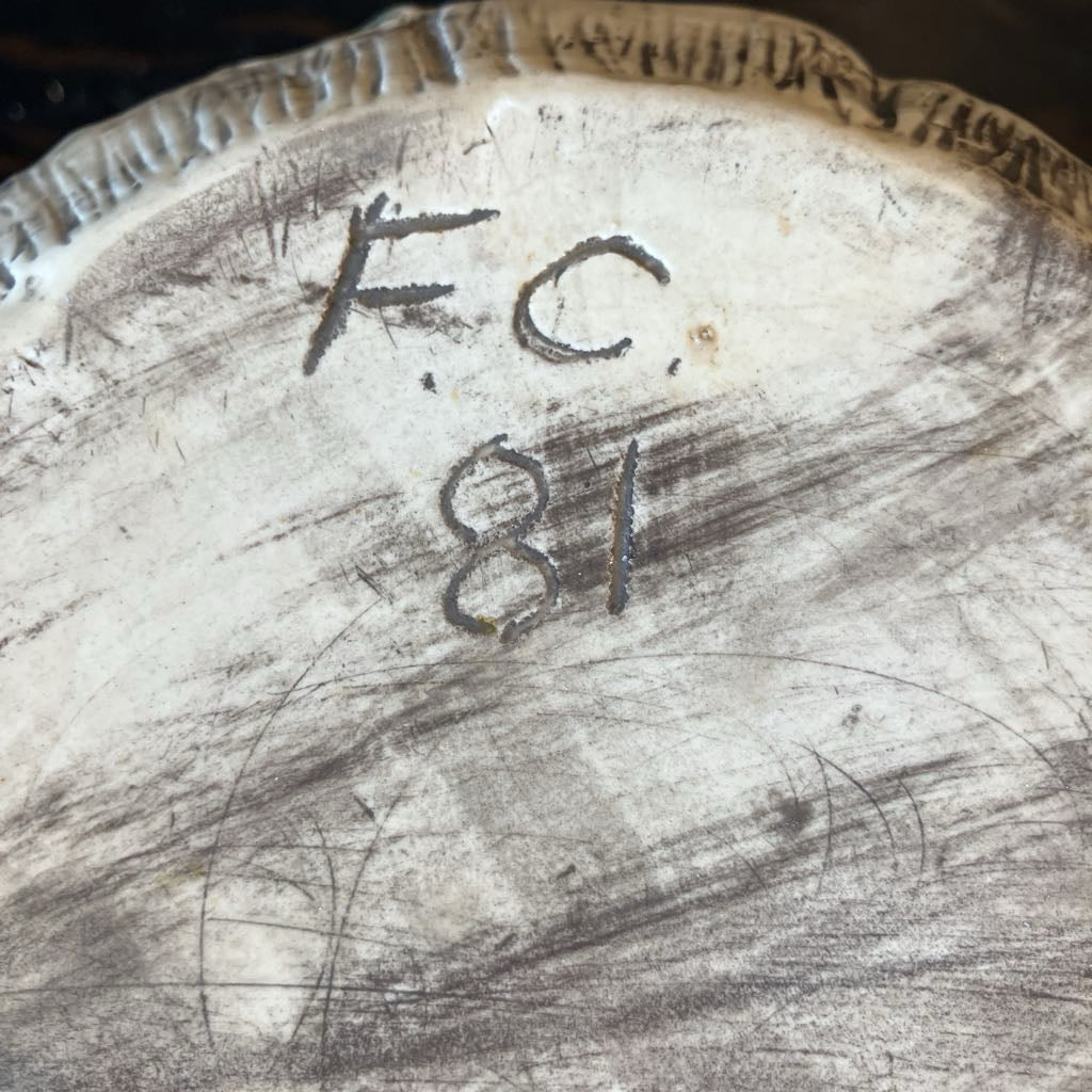 Close-up of a textured surface with 'F.C.' and number '81' engraved.