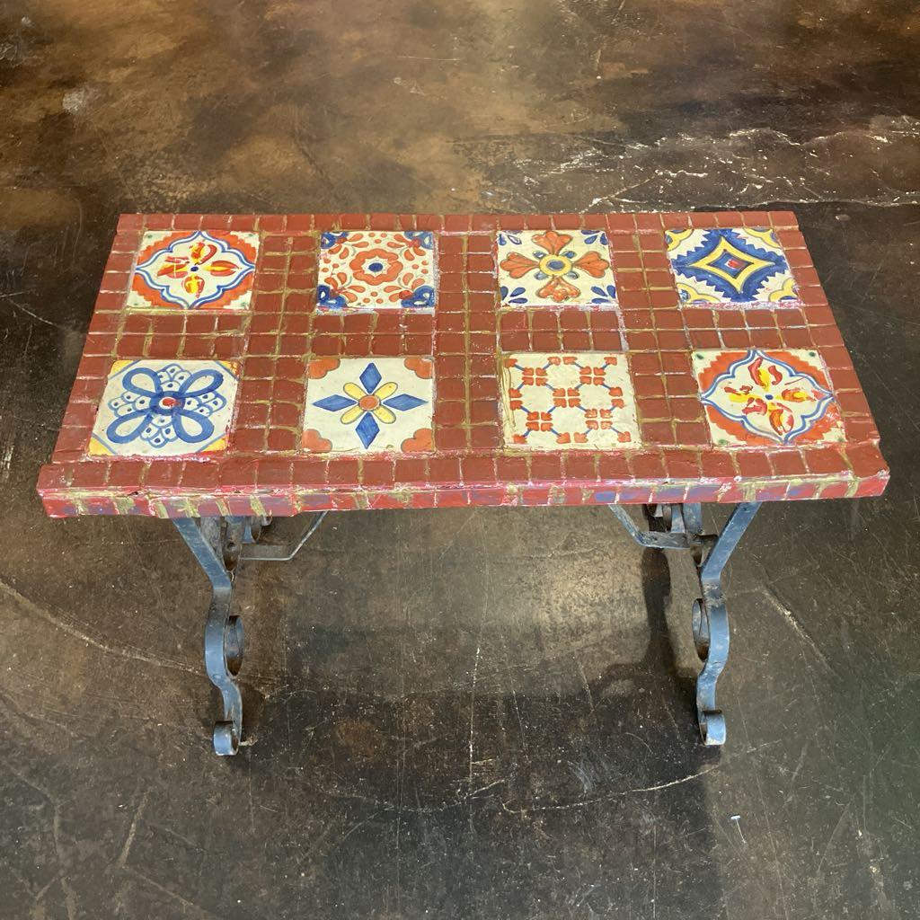 Table with decorative tile top on a dark floor
