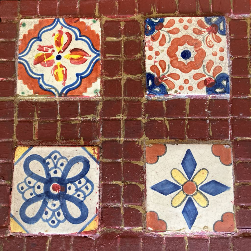 Decorative tiles with floral patterns on a brick wall.