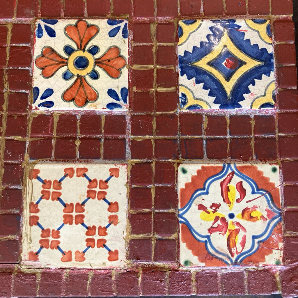 Decorative tiles with floral patterns on a red brick background