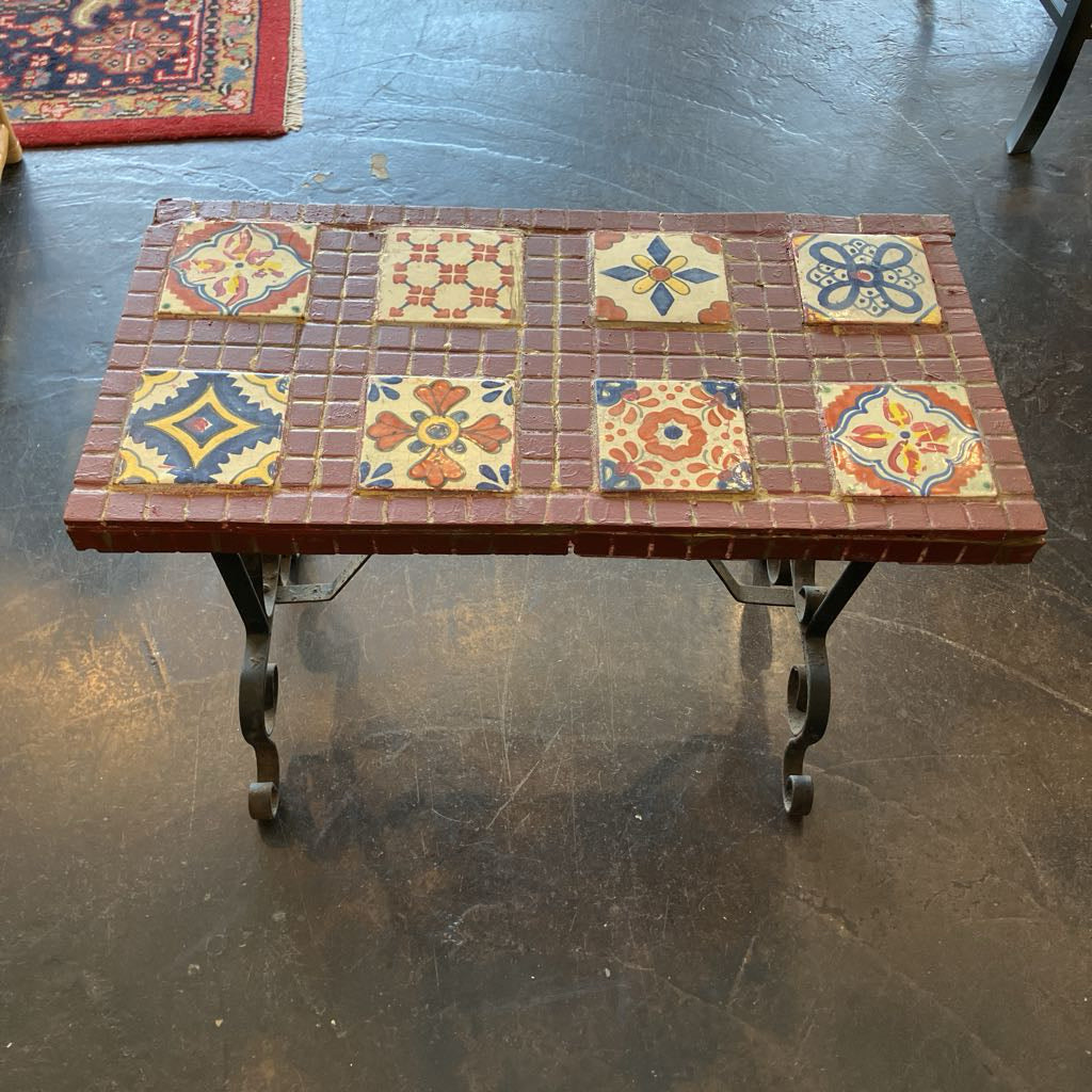 Table with decorative tiles on a dark floor