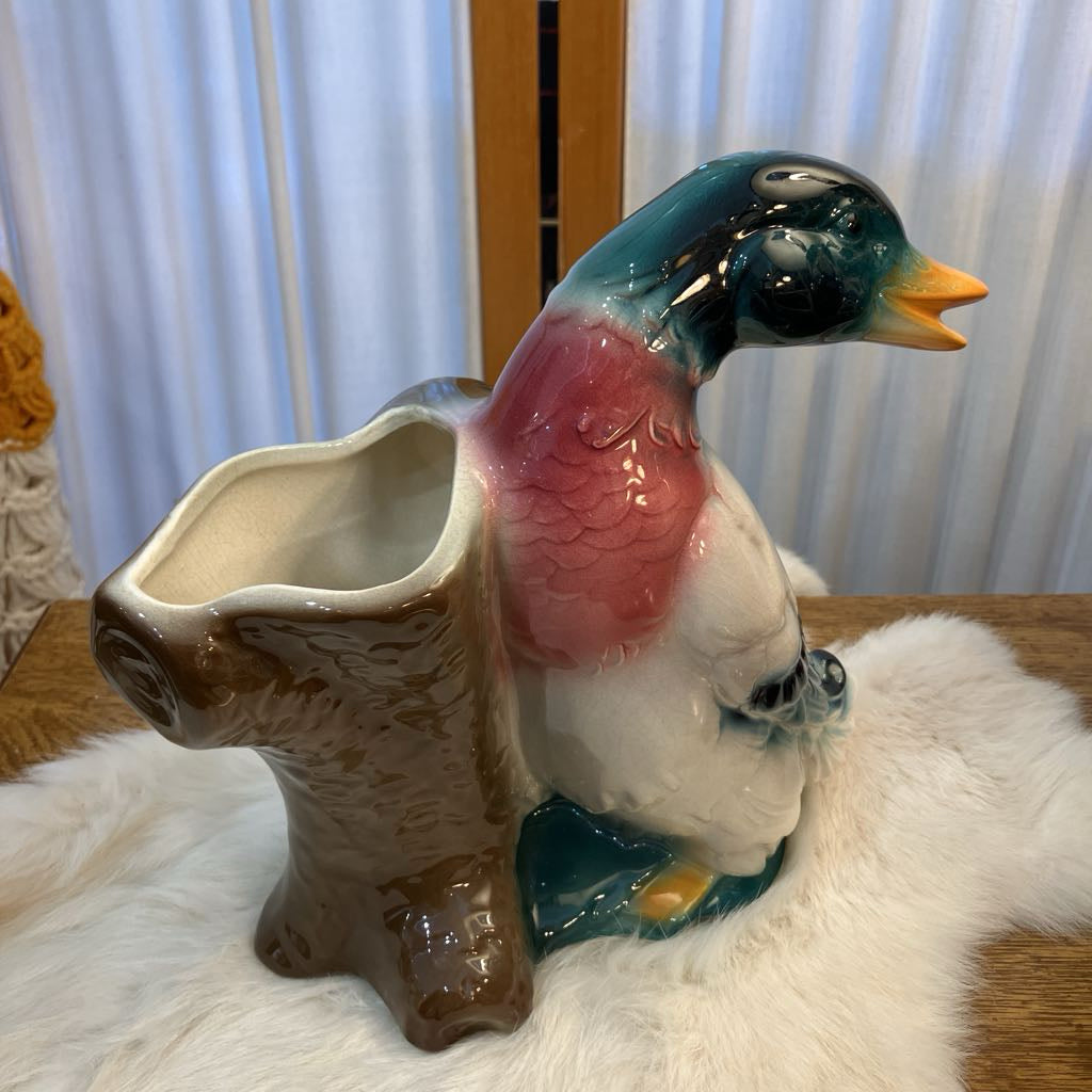 Ceramic duck-shaped pitcher on a white surface with a blurred background