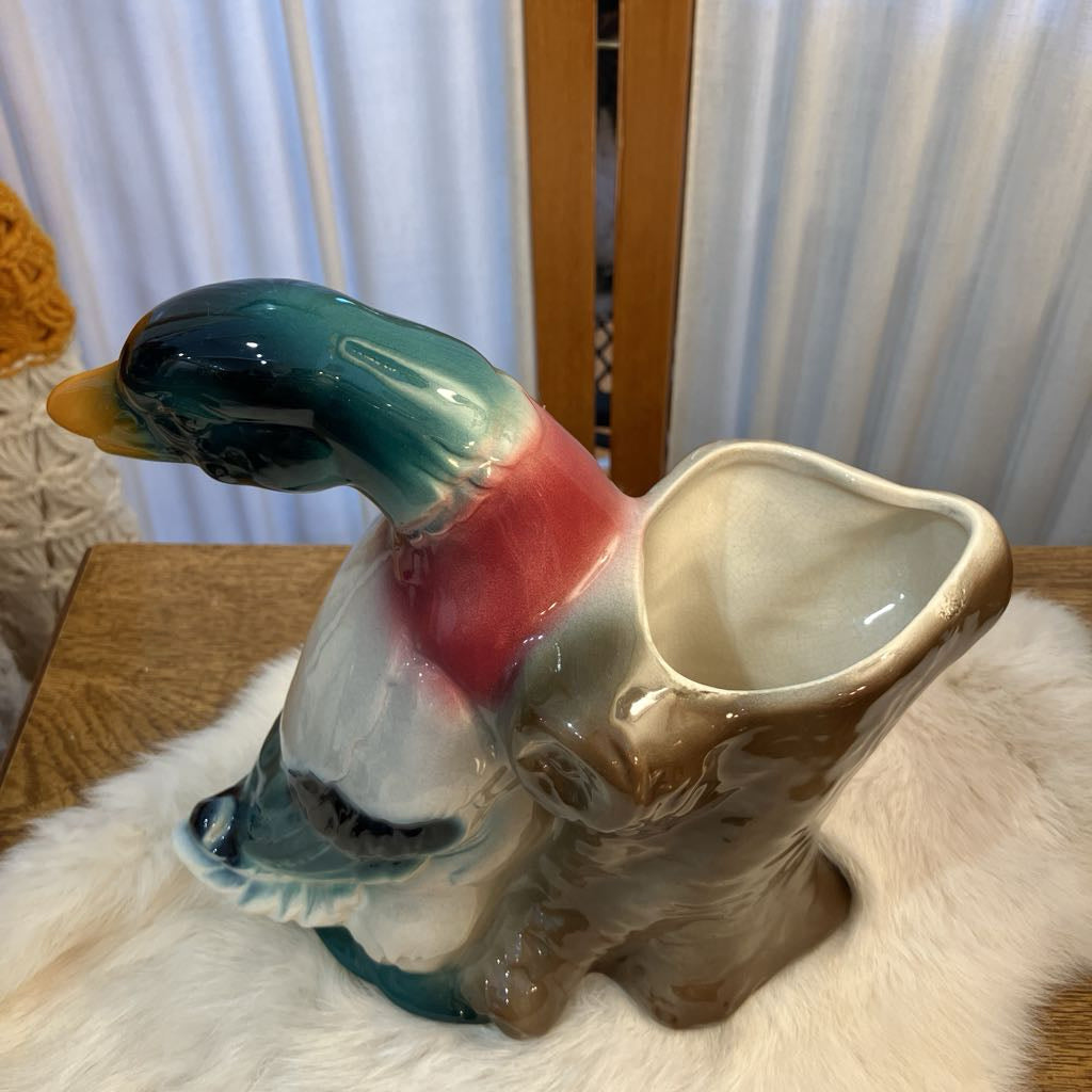 Ceramic duck-shaped planter on a white surface with a blurred background