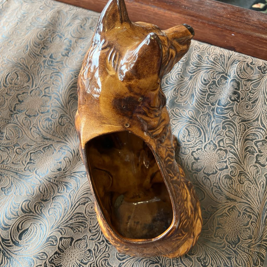 Brown ceramic dog-shaped object on a patterned fabric background