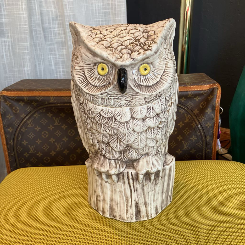 Decorative owl figurine on a yellow surface with a patterned background