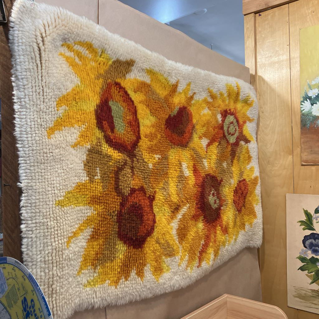Decorative rug with sunflower pattern on a wooden wall.