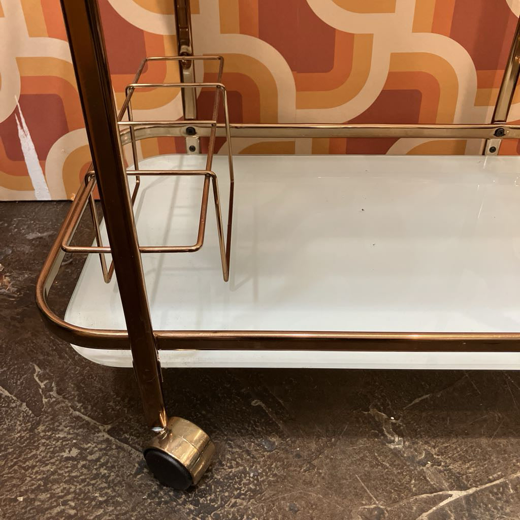 Metal bar cart with a tray against a patterned wall.