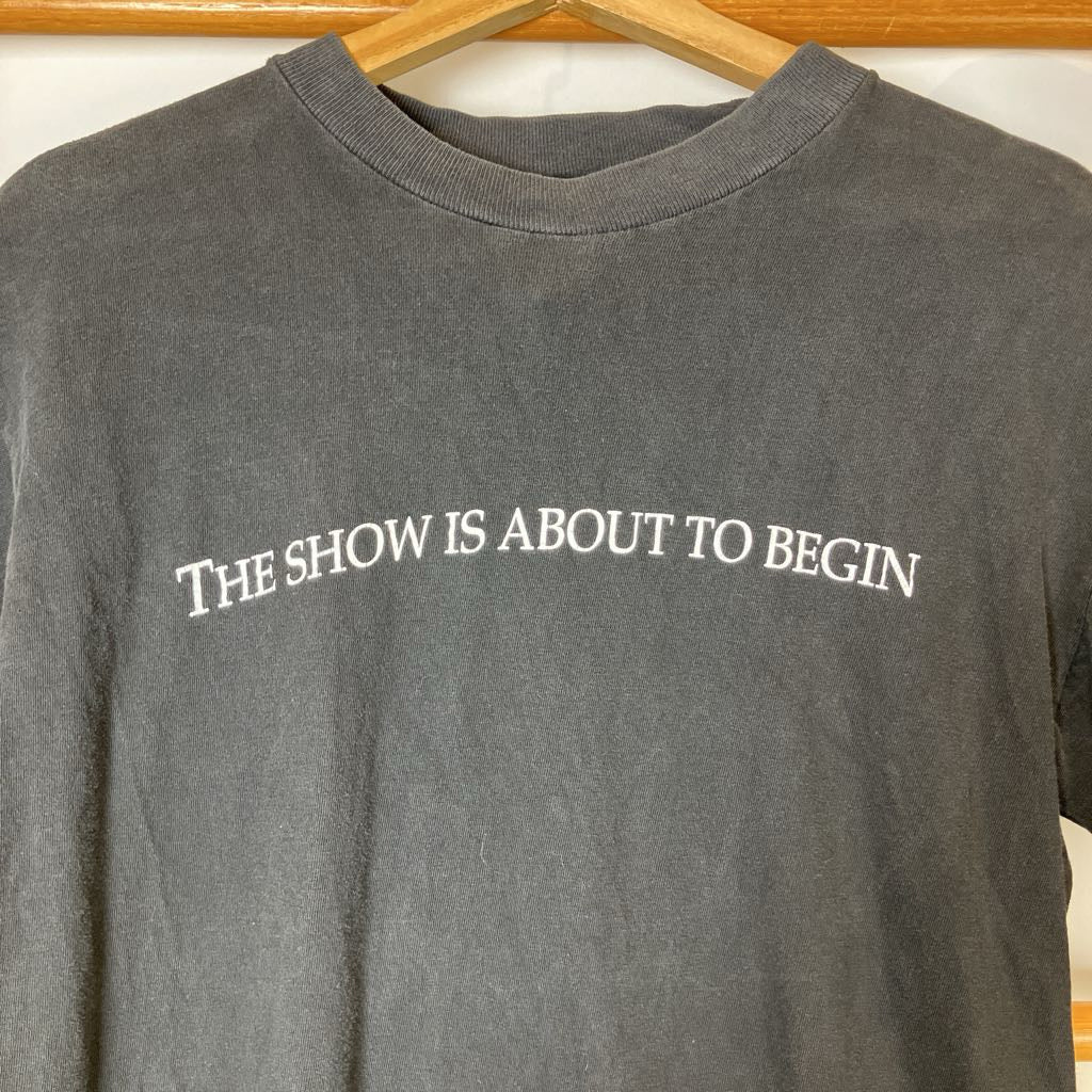 Gray sweatshirt with 'THE SHOW IS ABOUT TO BEGIN' text on a hanger.