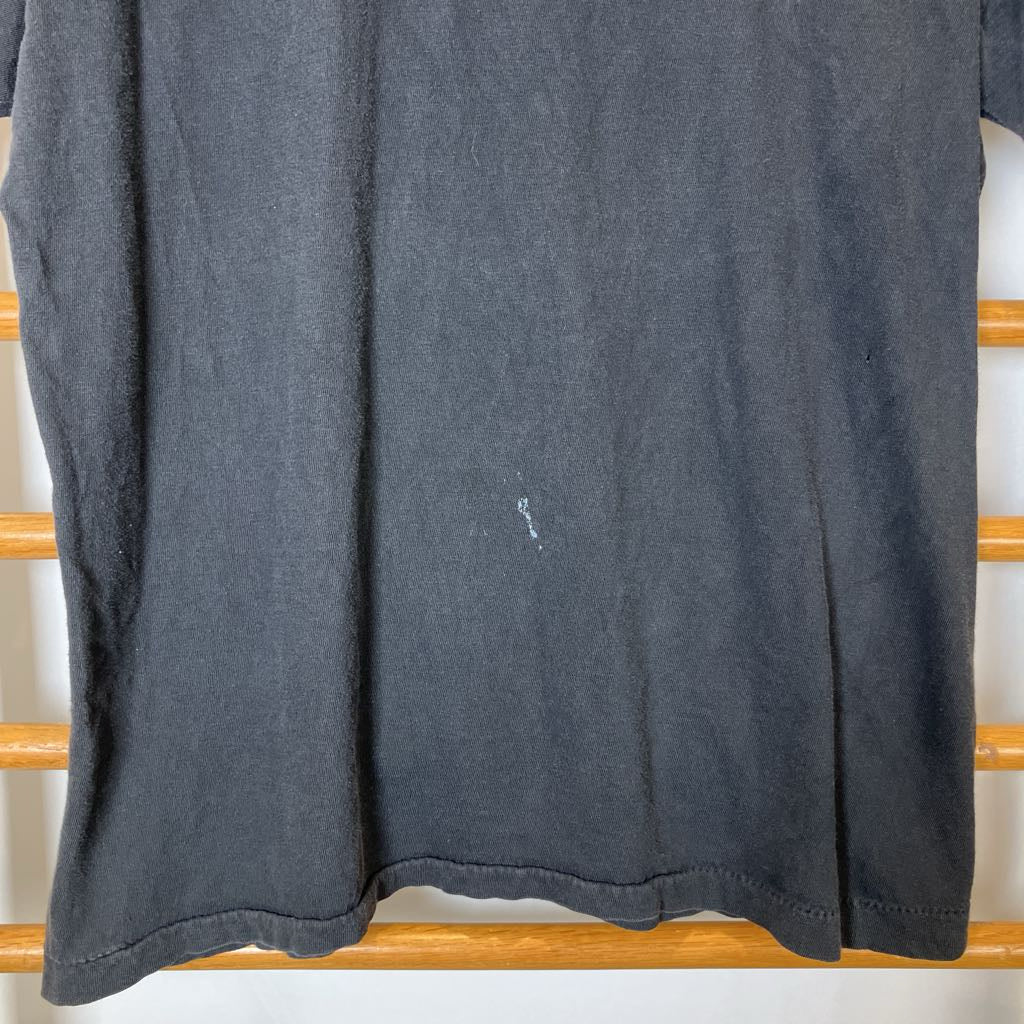 Dark gray t-shirt on a wooden rack with a small stain.
