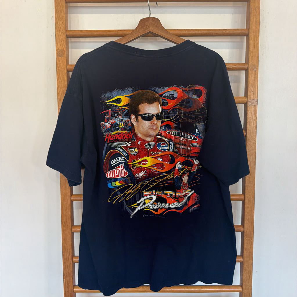 Black t-shirt with racing-themed design on a wooden hanger against a white wall