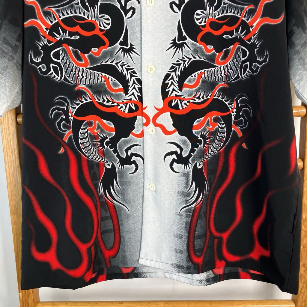 A black button-up shirt featuring a symmetrical graphic print of two white and gray dragons facing each other, with vibrant red flame-like accents and a gray-and-white striped center panel.