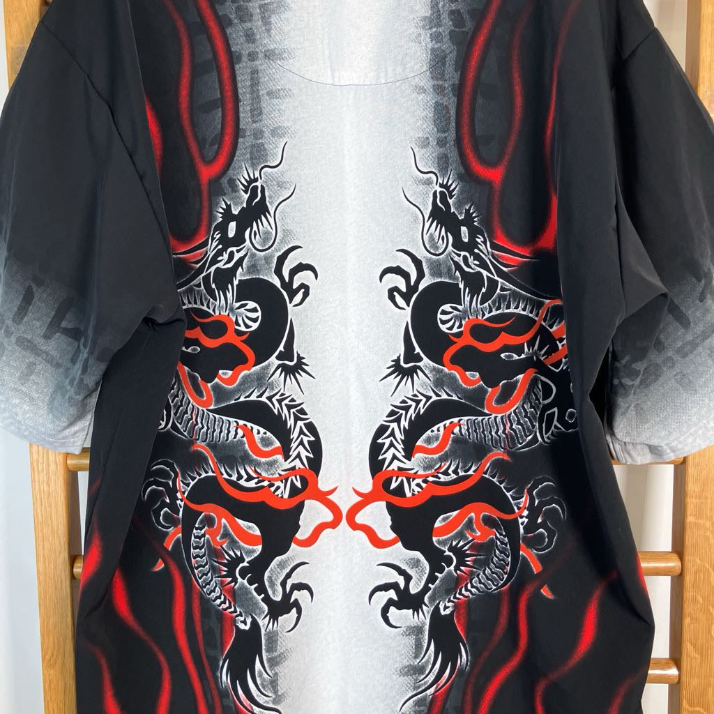 A black short-sleeve t-shirt featuring a symmetrical graphic print of two stylized dragons in white and gray with red accents, displayed on a wooden hanger.