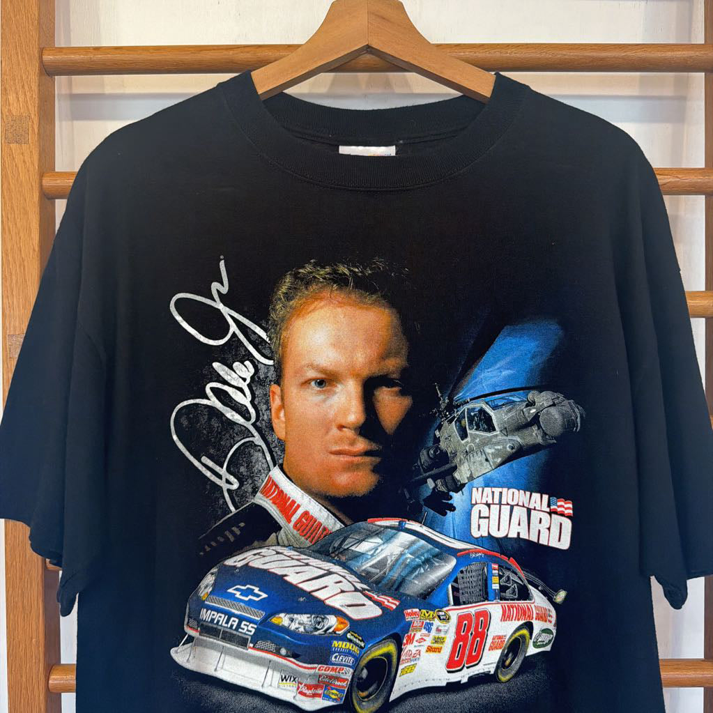 Black t-shirt with a graphic of a race car driver and car on a hanger.