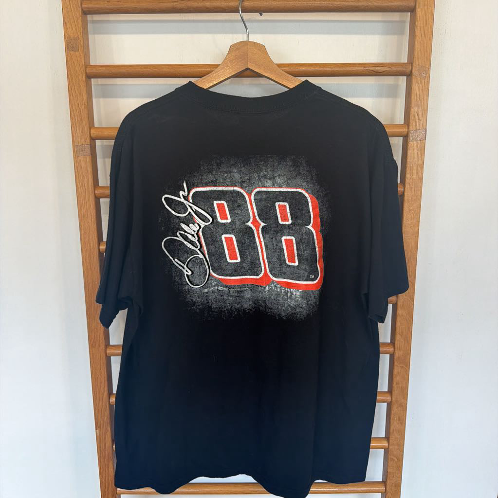 Black t-shirt with a graphic design on a wooden hanger against a white wall.
