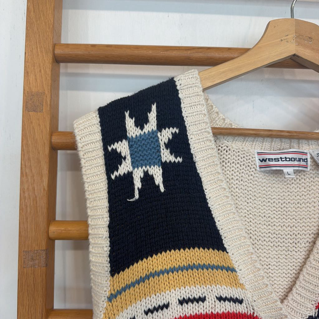 Knitted blanket with star design on a wooden hanger against a white wall.