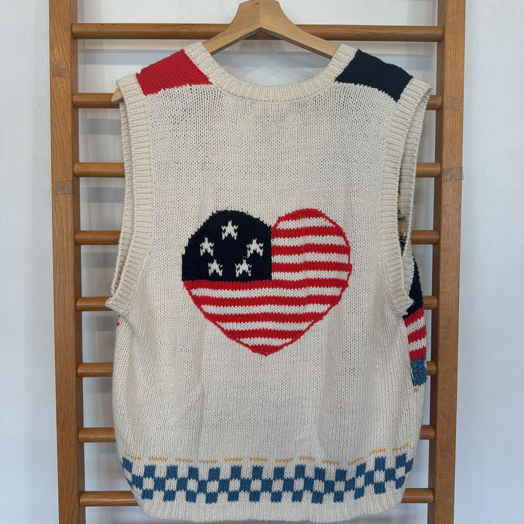 Knitted vest with American flag heart design on a wooden rack.