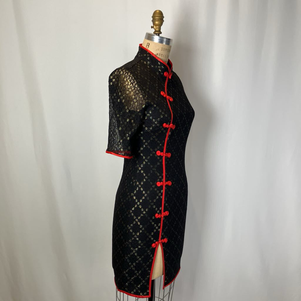 Black dress with red accents on a mannequin against a plain background