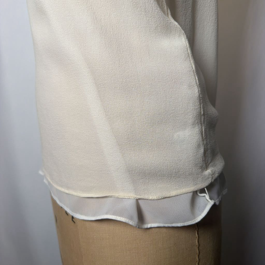 White blouse on a mannequin against a plain background