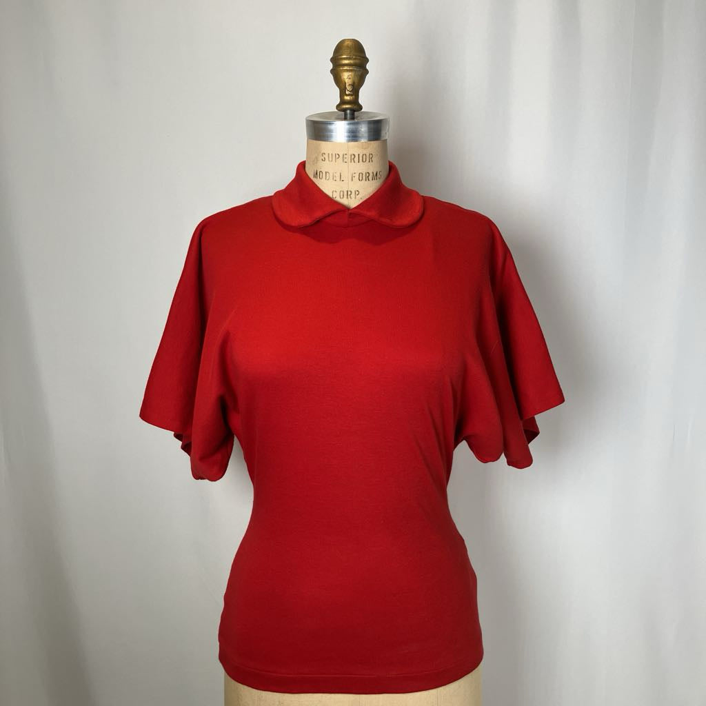 Red short-sleeve top on a mannequin against a plain background