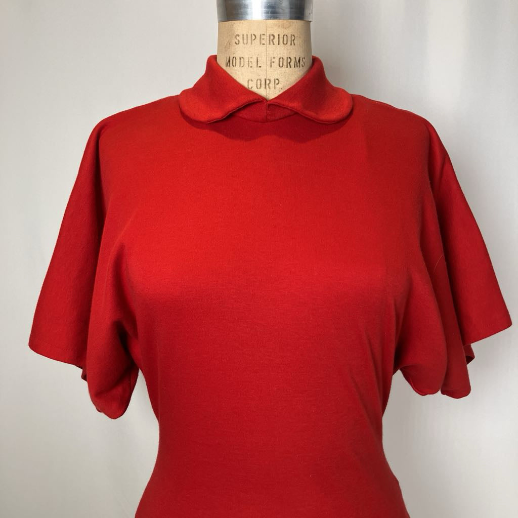 Red blouse on a mannequin against a plain background