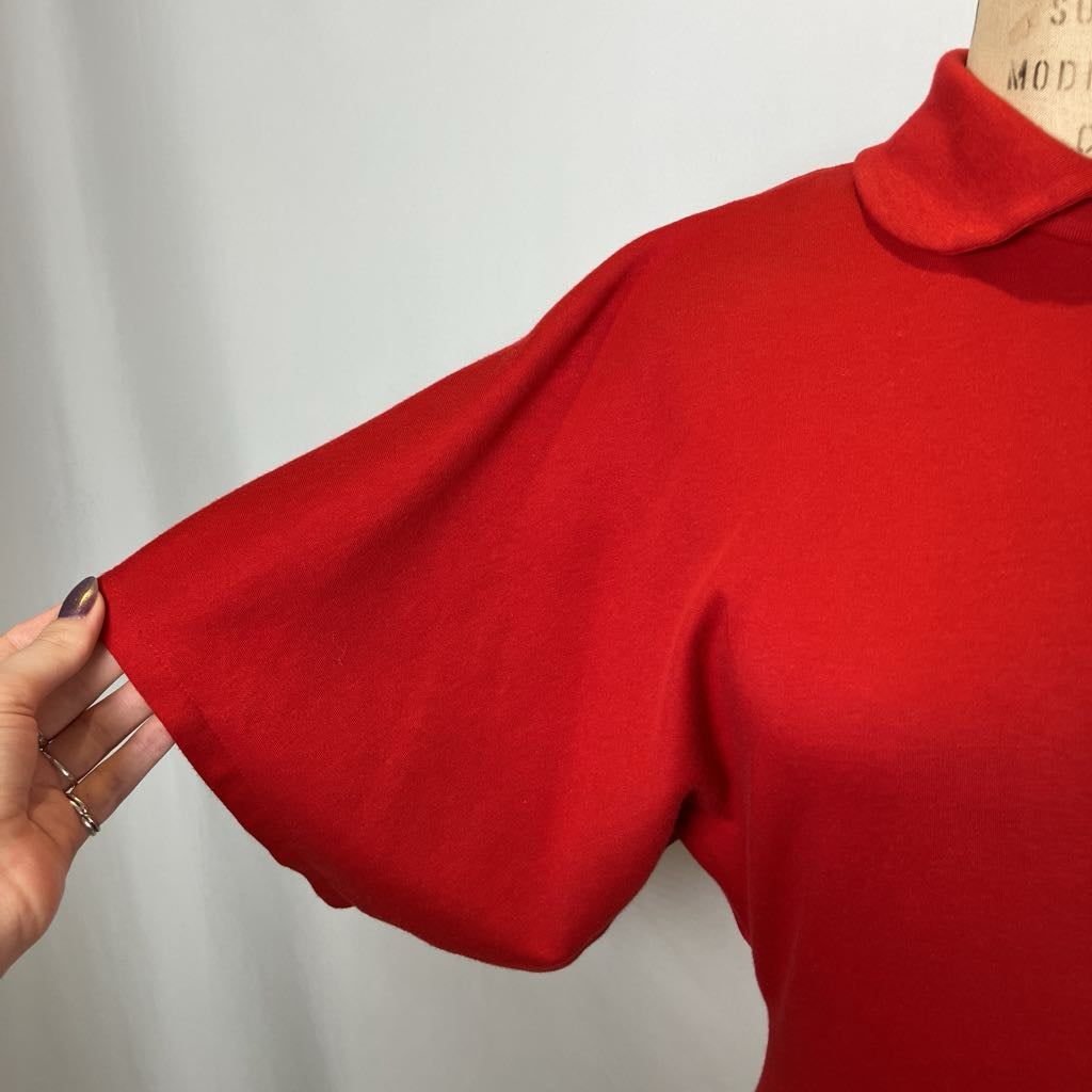 Red sweater with a turtleneck held up against a white background