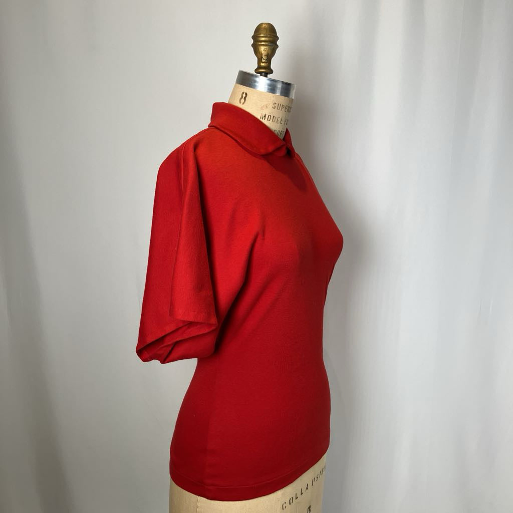 Red polo shirt on a mannequin against a plain background