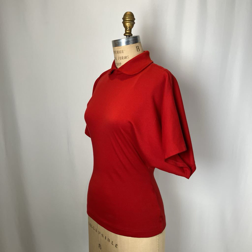 Red shirt on a mannequin against a plain background