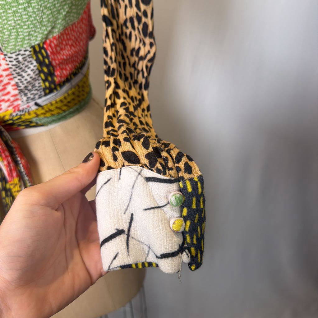 Hand holding a small fabric item with a leopard print strap against a neutral background