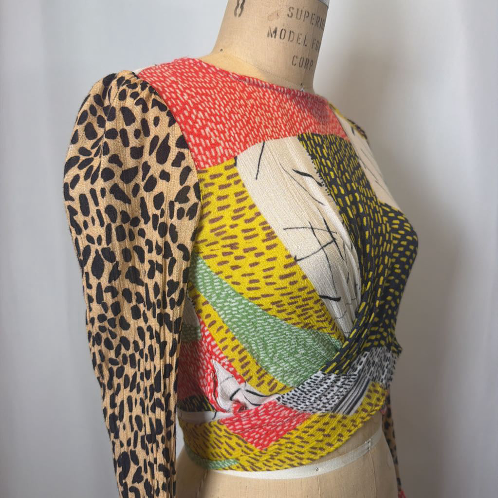Mannequin wearing a colorful patterned top with leopard print sleeves on a plain background