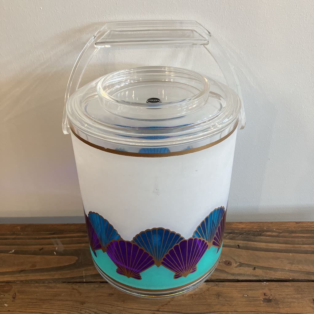 Clear glass container with decorative shell pattern on a wooden surface