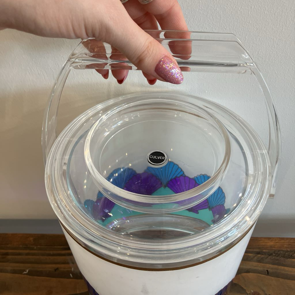 Clear container with colorful interior, held by a hand with glittery nail polish.