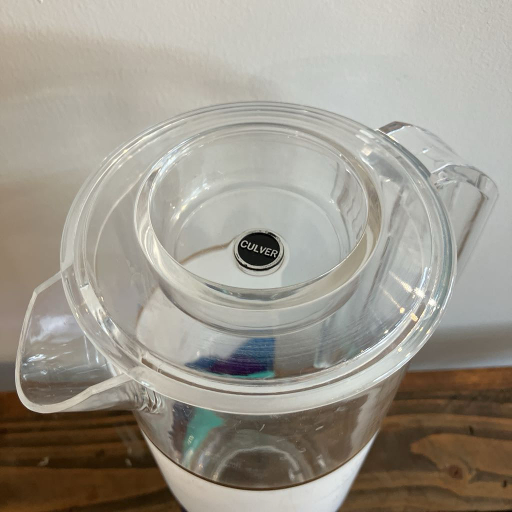 Clear pitcher with a visible brand logo on a wooden surface